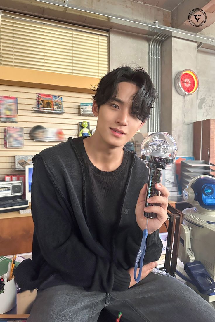 a young man sitting in front of a mirror holding a glass ball with a clock on it