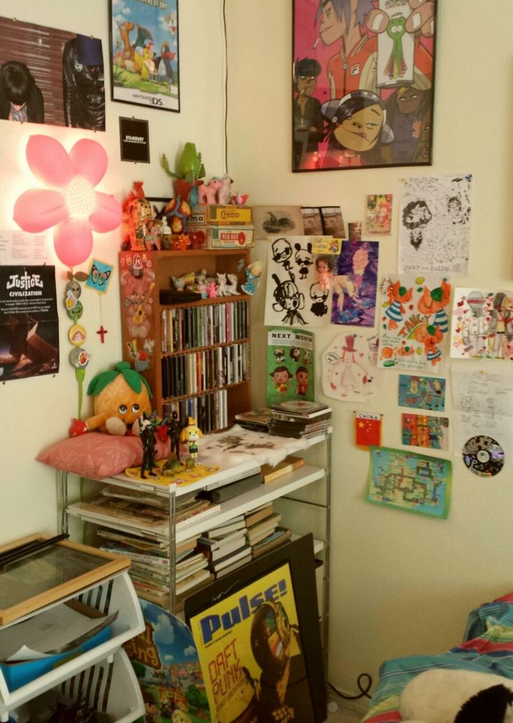 a room filled with lots of clutter and posters on the wall next to a bed