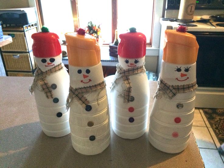 three snowmen made out of plastic bottles sitting on a counter