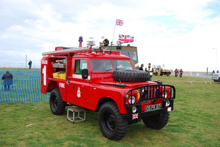 a red fire truck parked on top of a lush green field