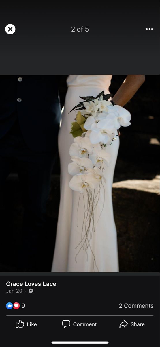 the bride and groom are standing together in their wedding dress with white flowers on it