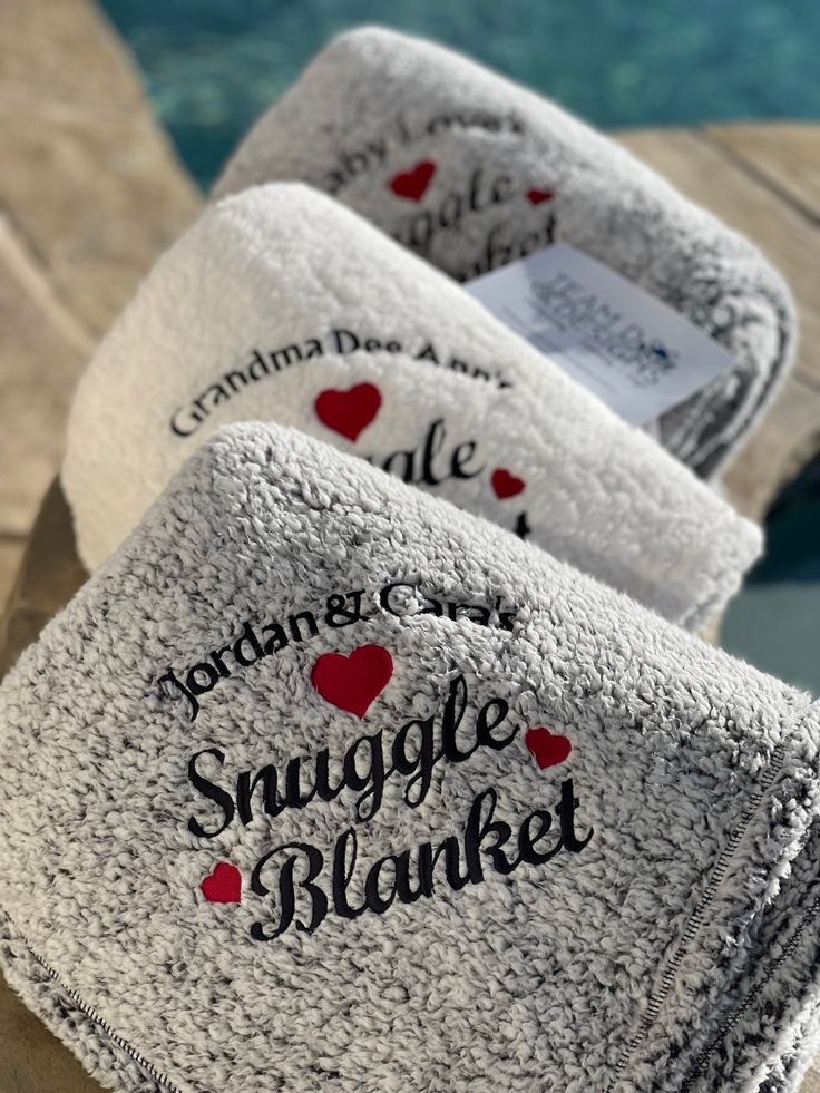 three personalized towels sitting on top of a table next to a pool with water in the background