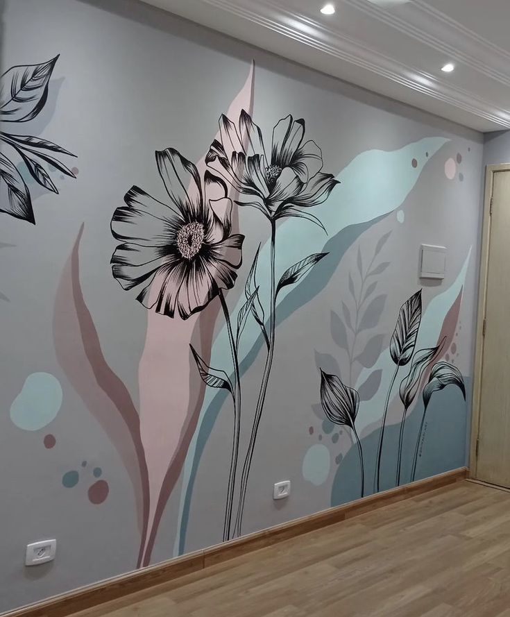 an empty room with flowers painted on the wall and wood flooring in front of it