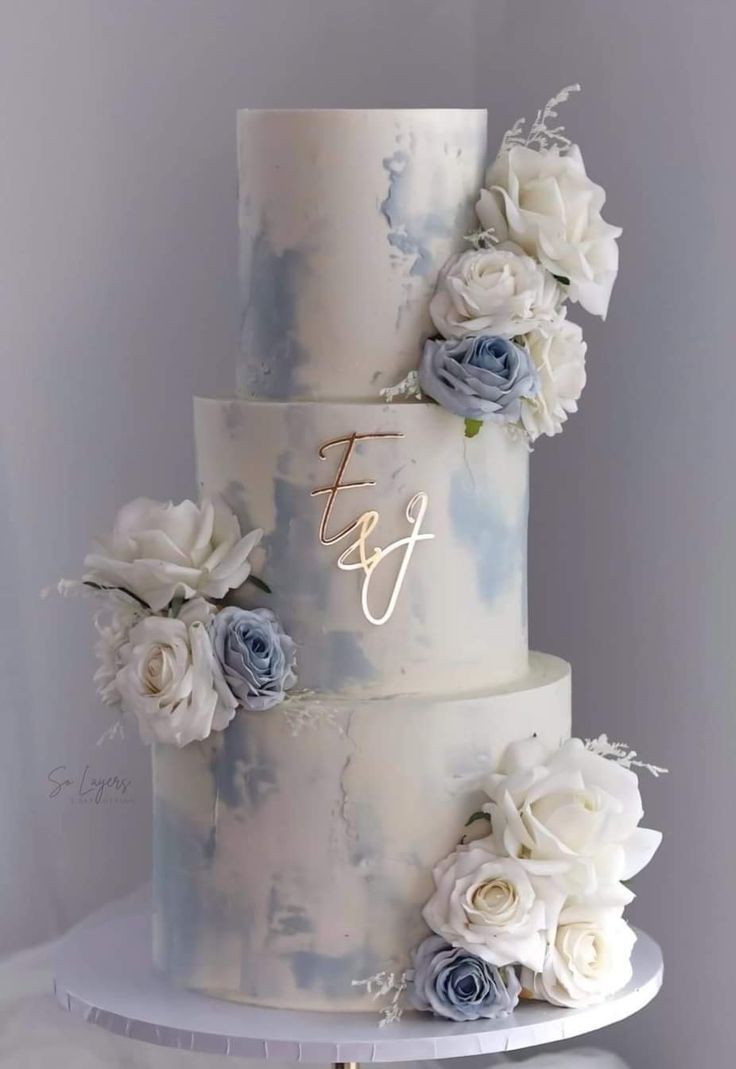 a three tiered wedding cake with blue and white flowers