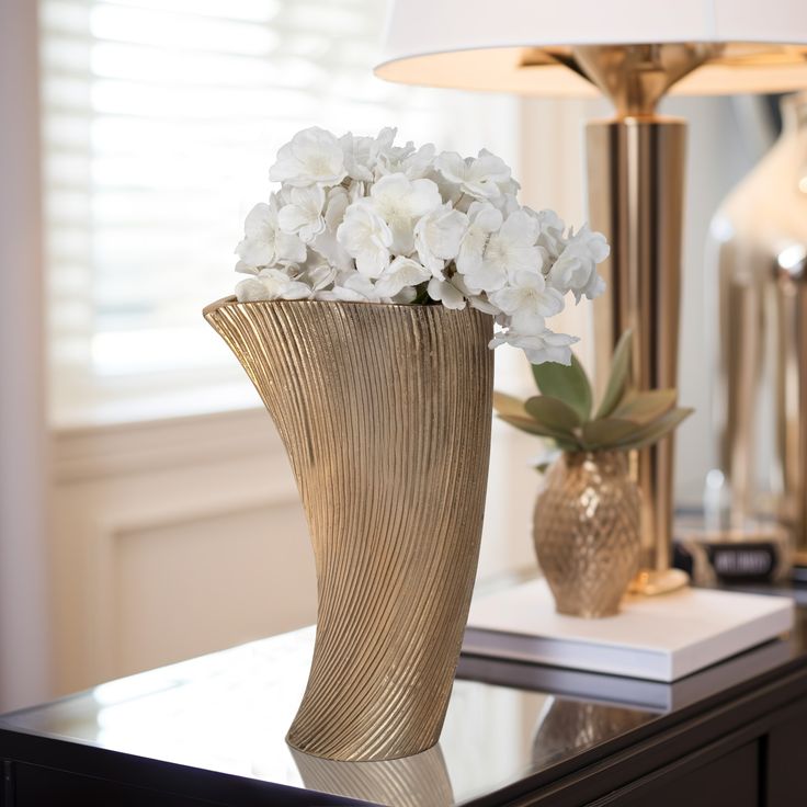 a gold vase with white flowers on a table