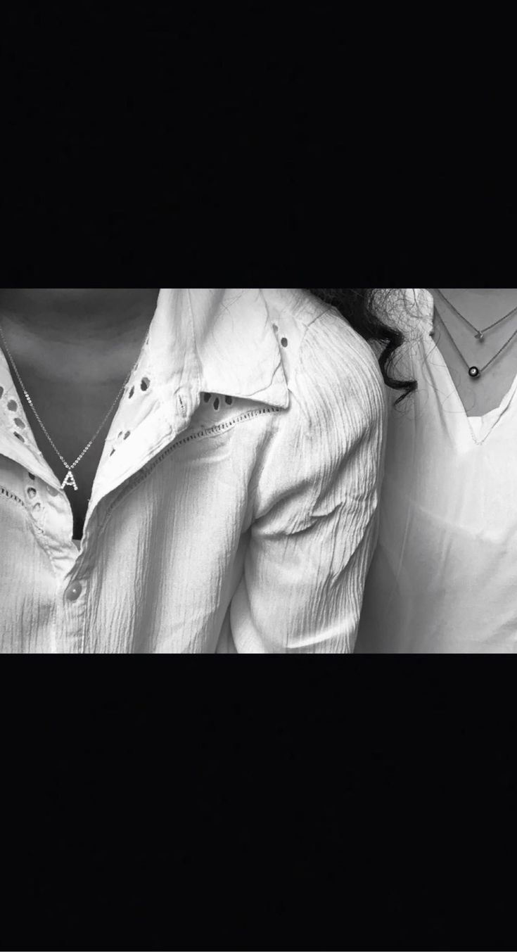 black and white photograph of two women with collared shirts over their shoulders, looking at the camera