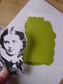 a person is holding up a piece of paper with green paint on it and the image of a woman's face