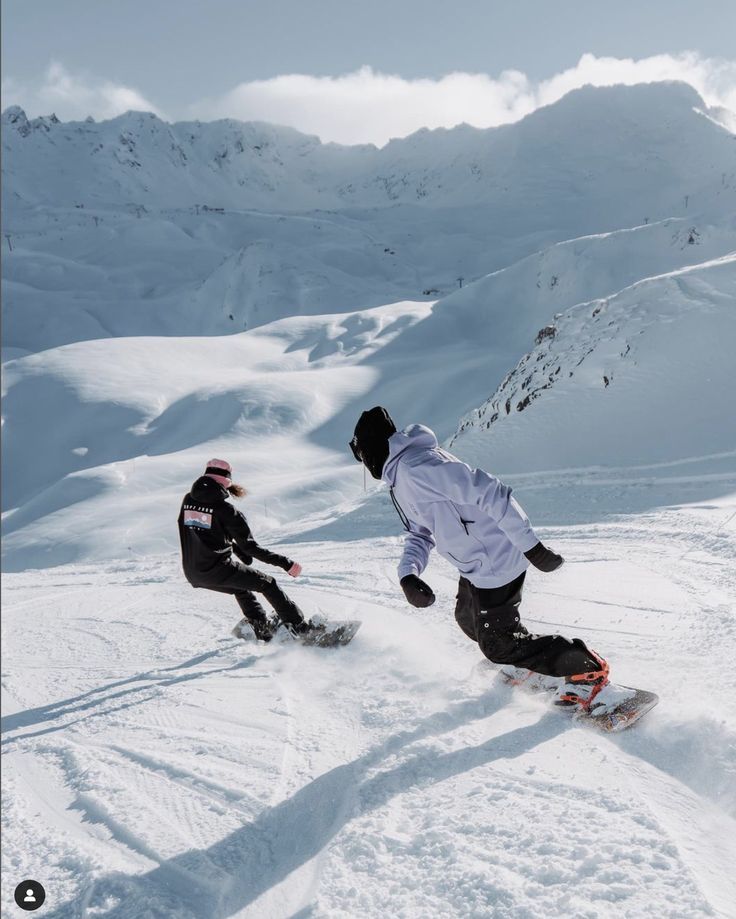 two snowboarders are going down a snowy hill