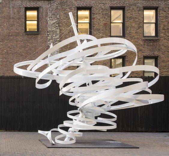 a large white sculpture sitting in front of a tall brick building on top of a sidewalk