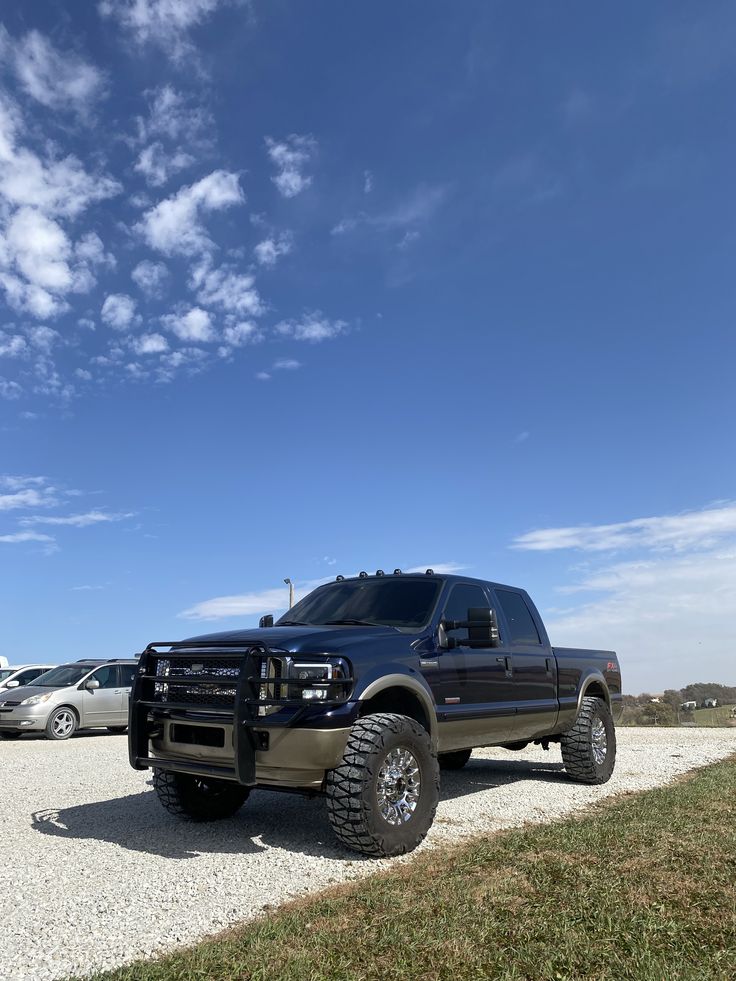 a large black truck parked on top of a gravel road