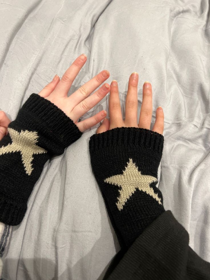 a person's hands with black and gold stars on them