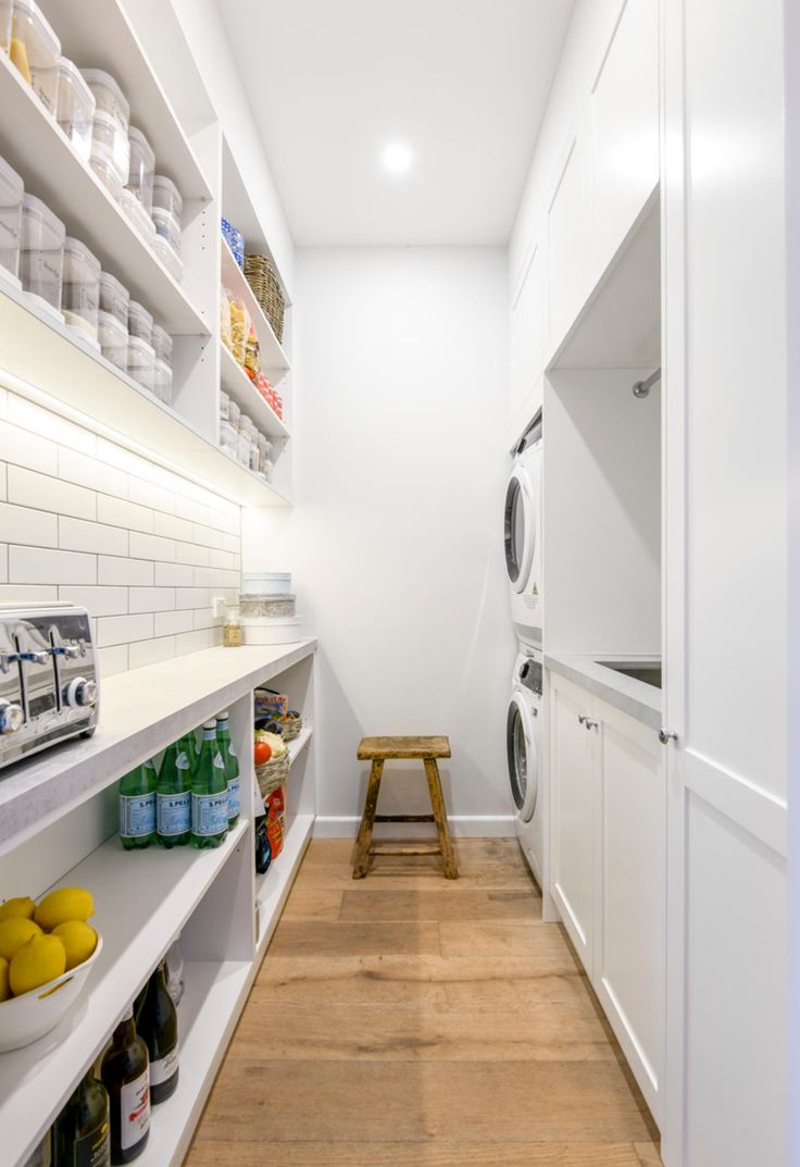 a laundry room with white shelving and wooden flooring