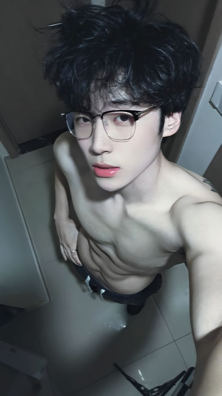 a shirtless man with glasses posing for the camera