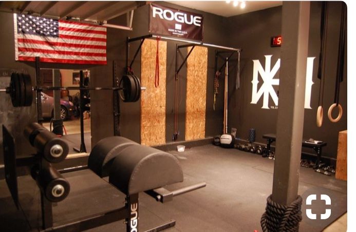 a gym with an american flag hanging on the wall and other equipment in front of it