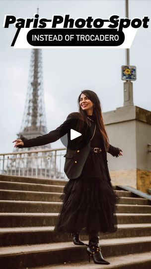 a woman standing on some steps in front of the eiffel tower with her arms outstretched