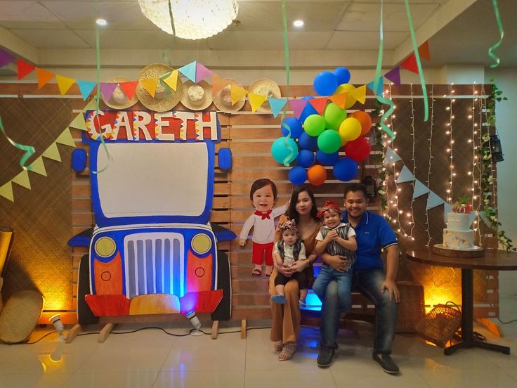 the family is posing for a photo in front of their birthday cake and balloon decorations