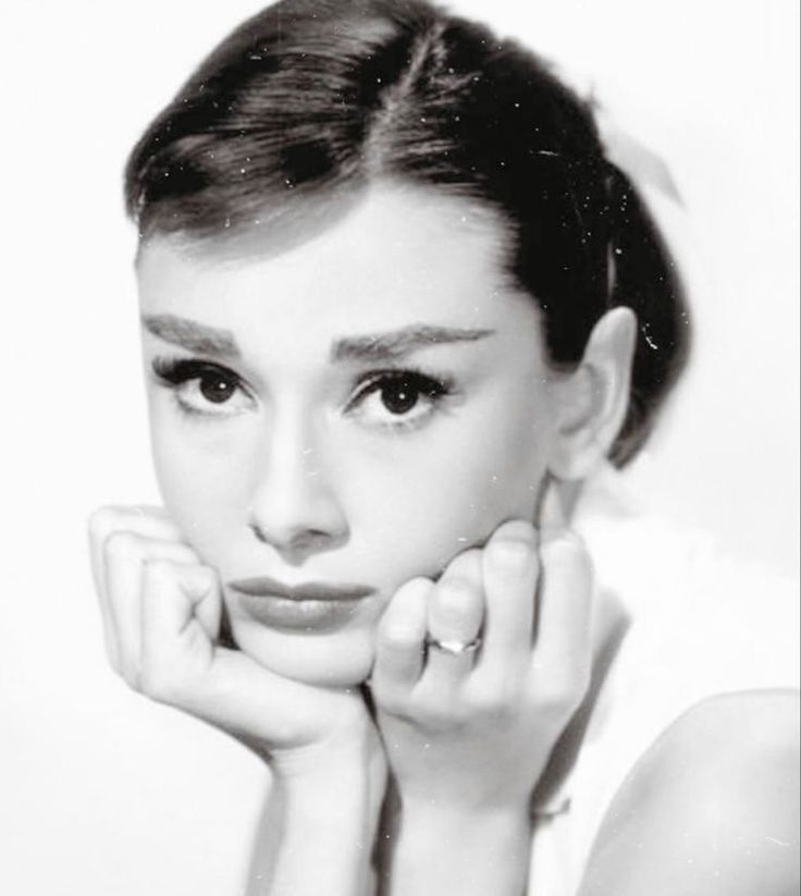 black and white photograph of a woman with her hands on her face, looking at the camera