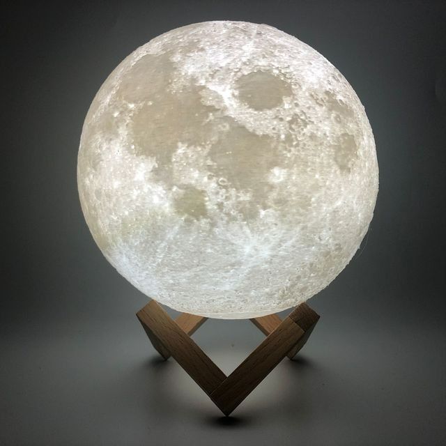 the moon lamp is sitting on top of a wooden stand