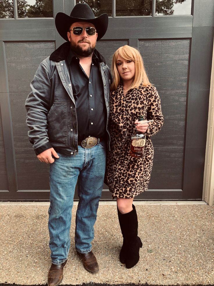 a man and woman standing next to each other in front of a garage door wearing cowboy hats