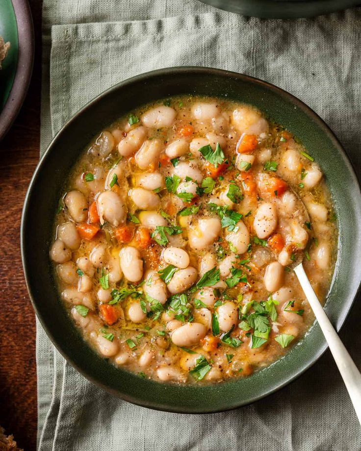 a bowl filled with beans and carrots on top of a table