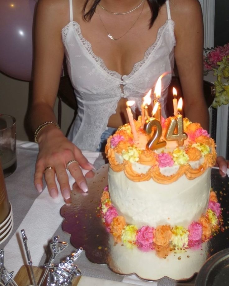 a woman sitting in front of a birthday cake with candles on it and the number twenty