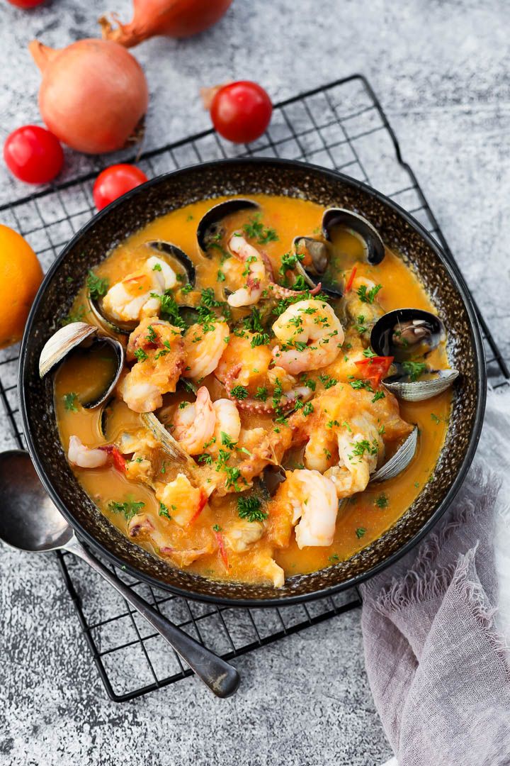 a bowl filled with seafood and clams on top of a wire rack next to tomatoes