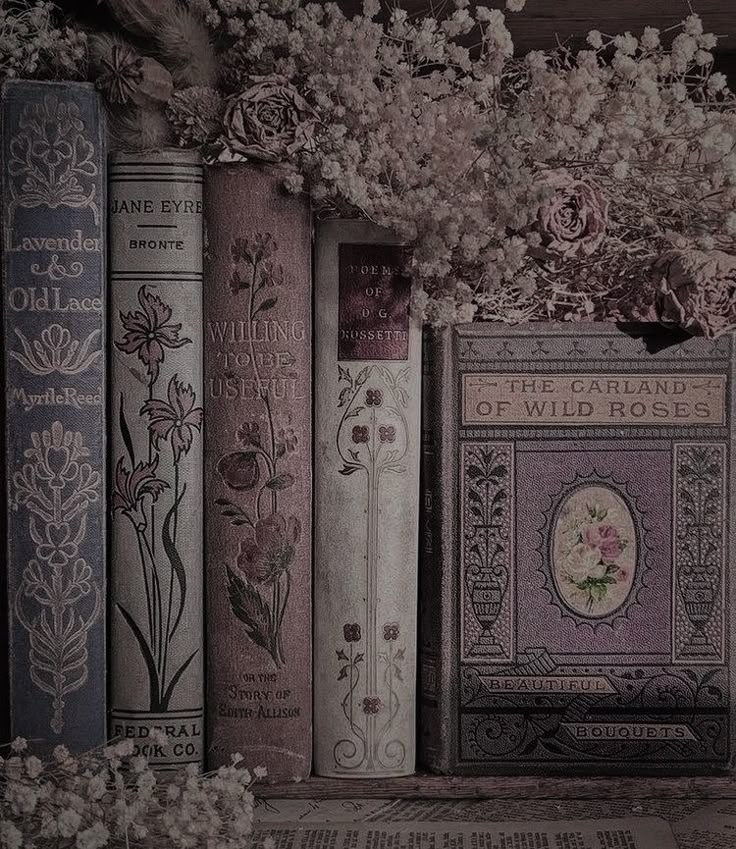 a row of old books sitting on top of a wooden shelf filled with flowers and plants