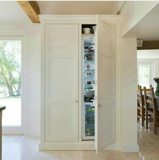 an open refrigerator in the middle of a kitchen with white walls and wood beams on the ceiling