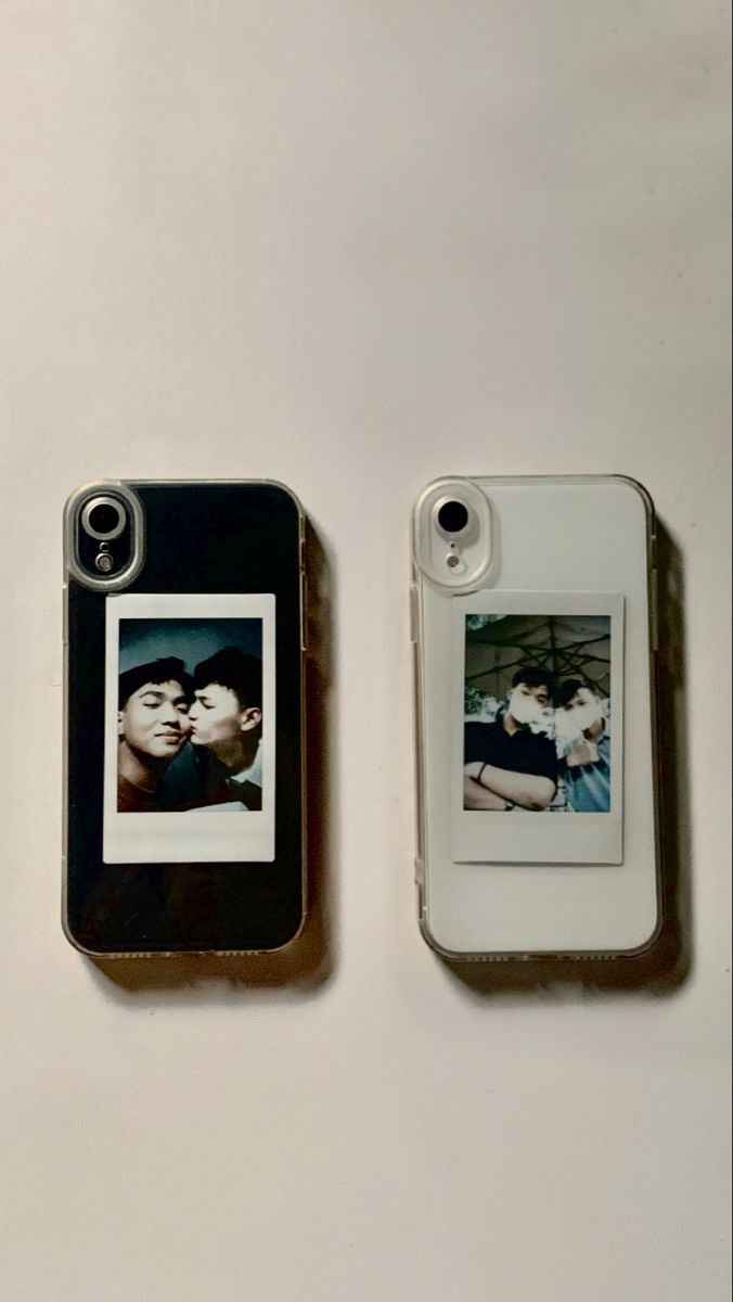 two cell phones sitting next to each other on a white surface, one with a photo and the other without