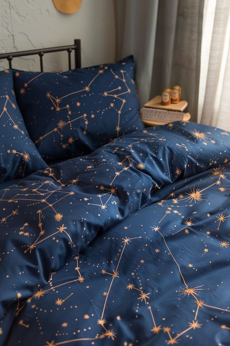 a bed with blue sheets and gold stars on it in front of a white wall