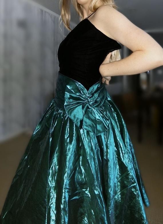 Fun 1980’s prom dress. Black velvet bodice and a green metallic skirt and large bow. One spaghetti shoulder strap. There is a rip in the metallic skirt, see photoBust: 28” (yes, 28” bust)Waist: 24”Hips: freeModel is 5’6” 80 Prom Dresses 1980s, 80’s Prom Dress, 80s Prom Aesthetic, 80s Prom Dress Costume, Ugly Prom Dress, Dresses 1980s, 1980s Prom Dress, 1980s Prom, Ugly Fashion