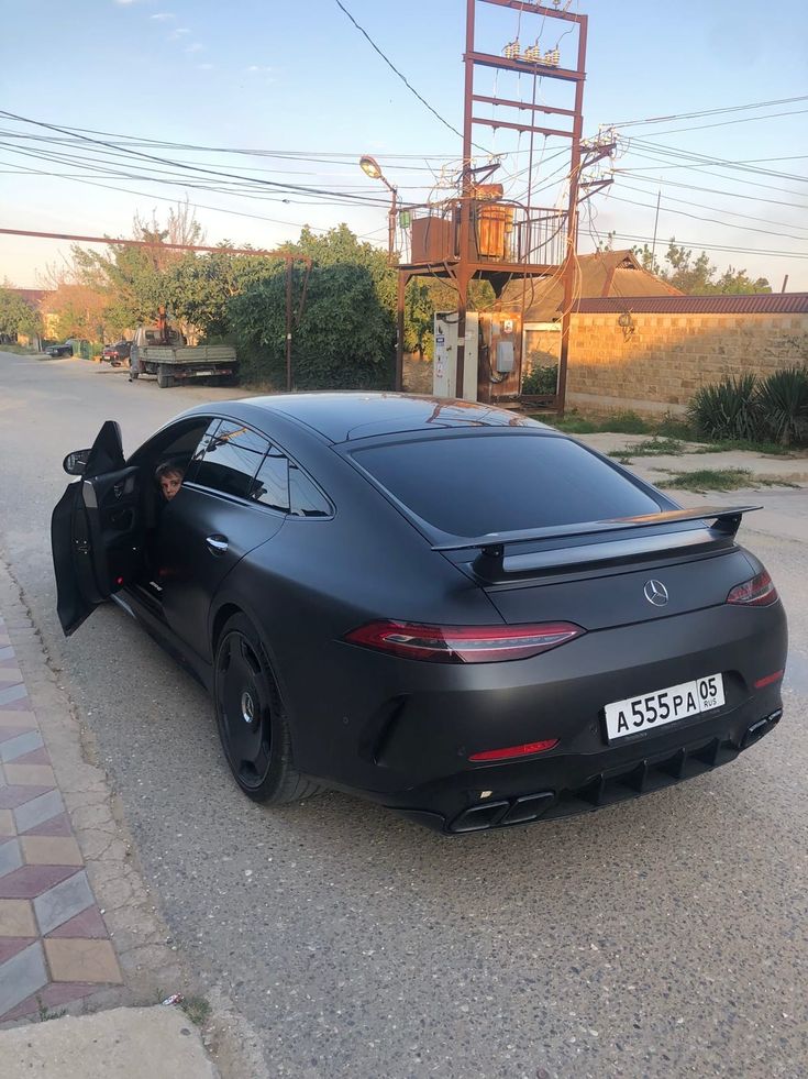 a black sports car is parked on the side of the road with its door open