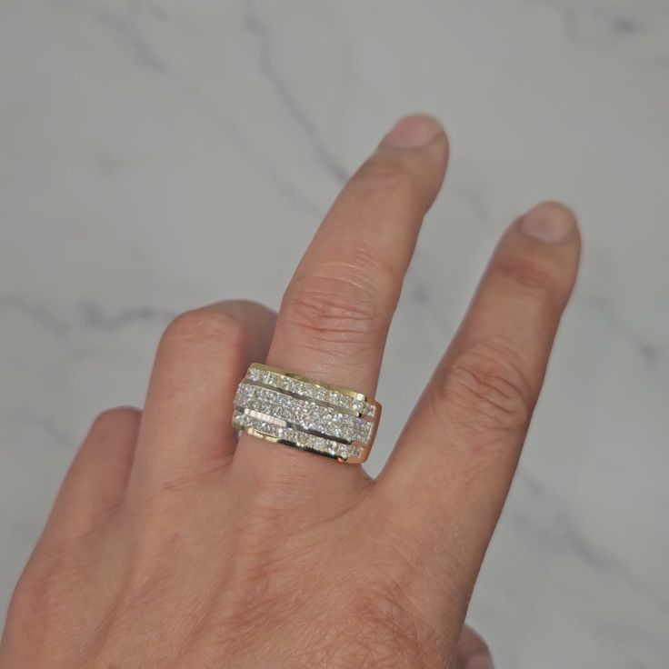 a person's hand with a diamond ring on top of their finger, in front of a marble background