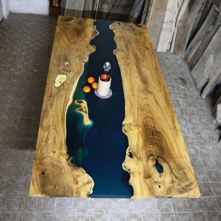 a table made out of wood with blue water in the center and two vases on top