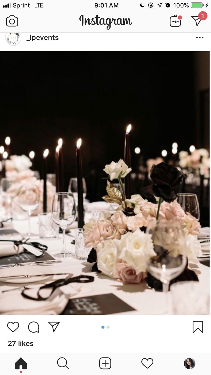 the table is set with white and pink flowers, black candles, and menus