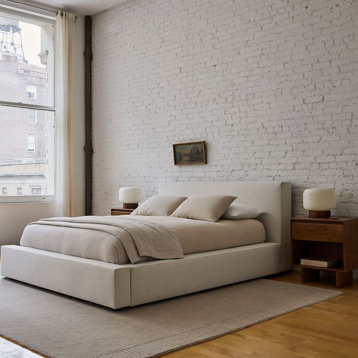 a bed sitting next to a window in a bedroom on top of a hard wood floor