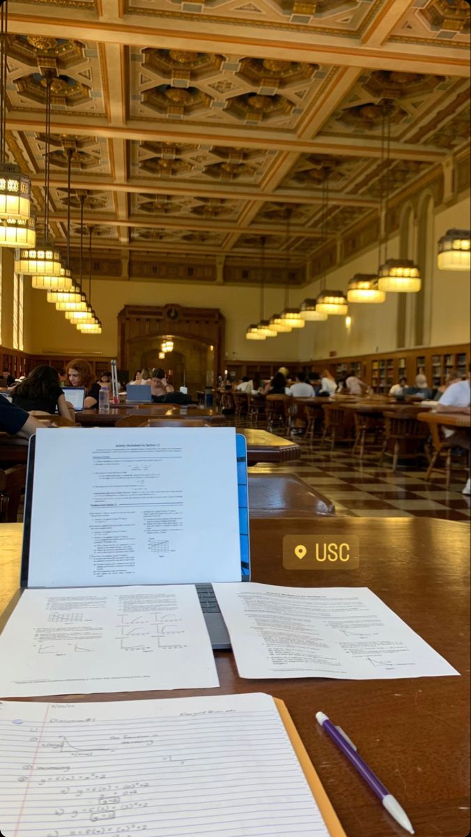 a table with papers on it and people sitting at tables in the background