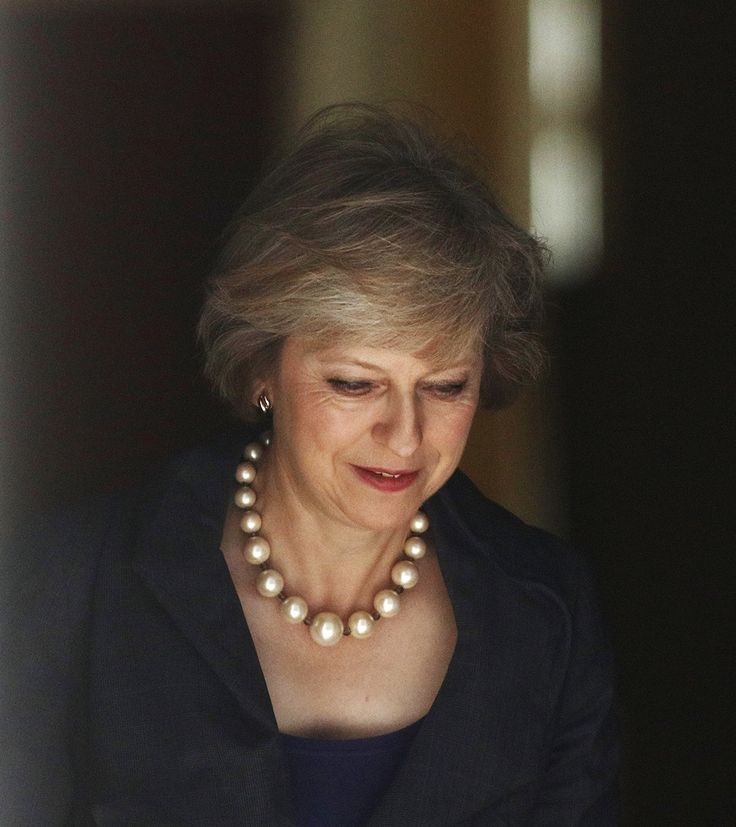 the queen of england looks down at her cell phone as she stands in front of an open doorway