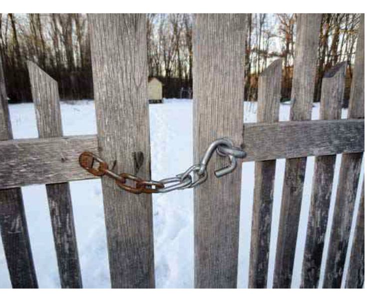 a wooden fence with a chain attached to it and snow on the ground behind it