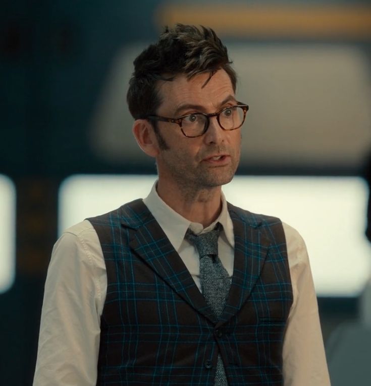 a man wearing glasses and a plaid vest