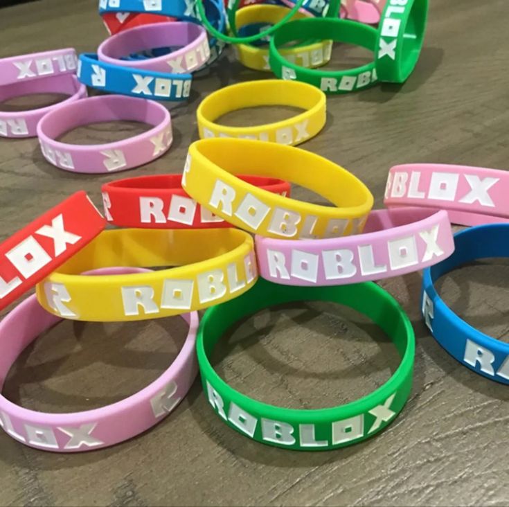 many different colored rubber bracelets on a wooden table with the words roblex and roblex printed on them