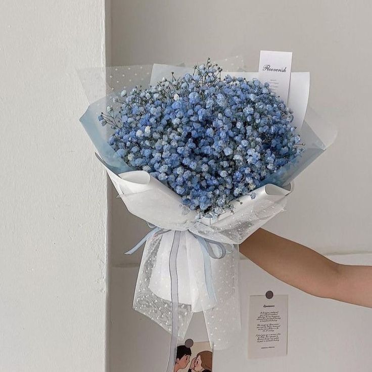 a person holding a bouquet of blue flowers