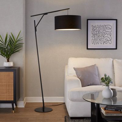 a living room with a white couch and a black lamp on the table in front of it