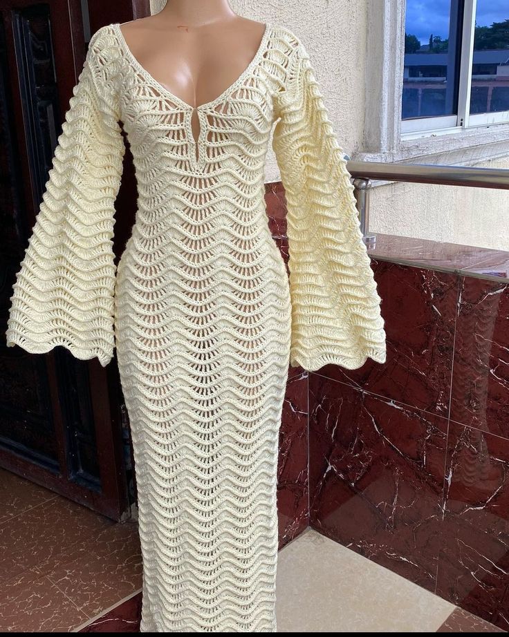 a white crocheted dress on display in front of a window