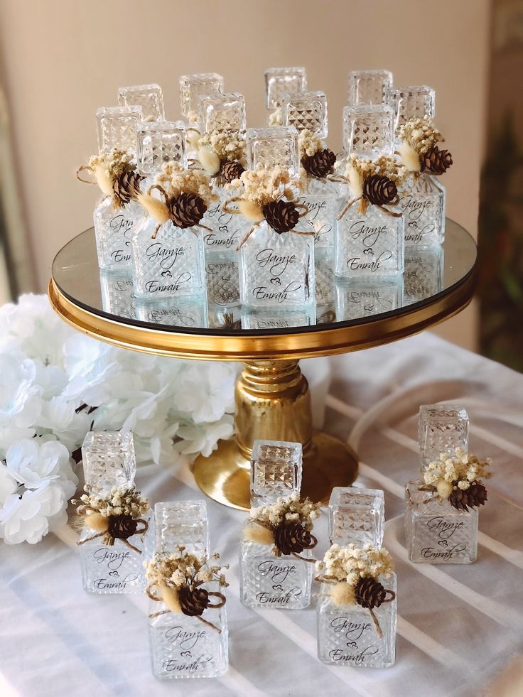 there are many small glass bottles on the table with pine cones and flowers in them