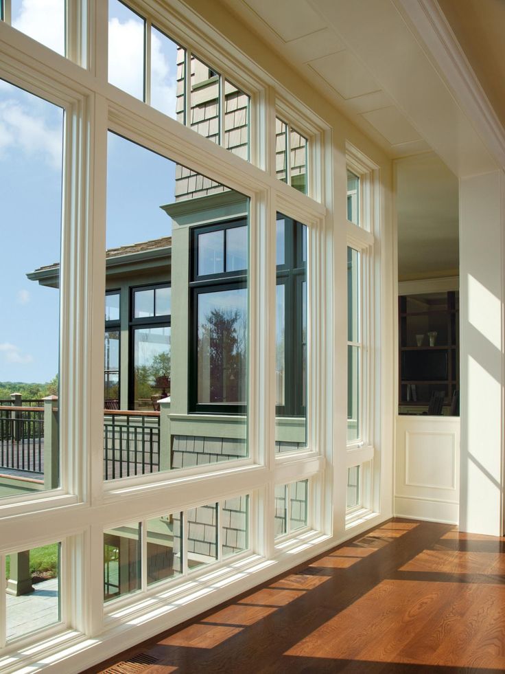 an empty room with large windows and hard wood flooring on the side of it