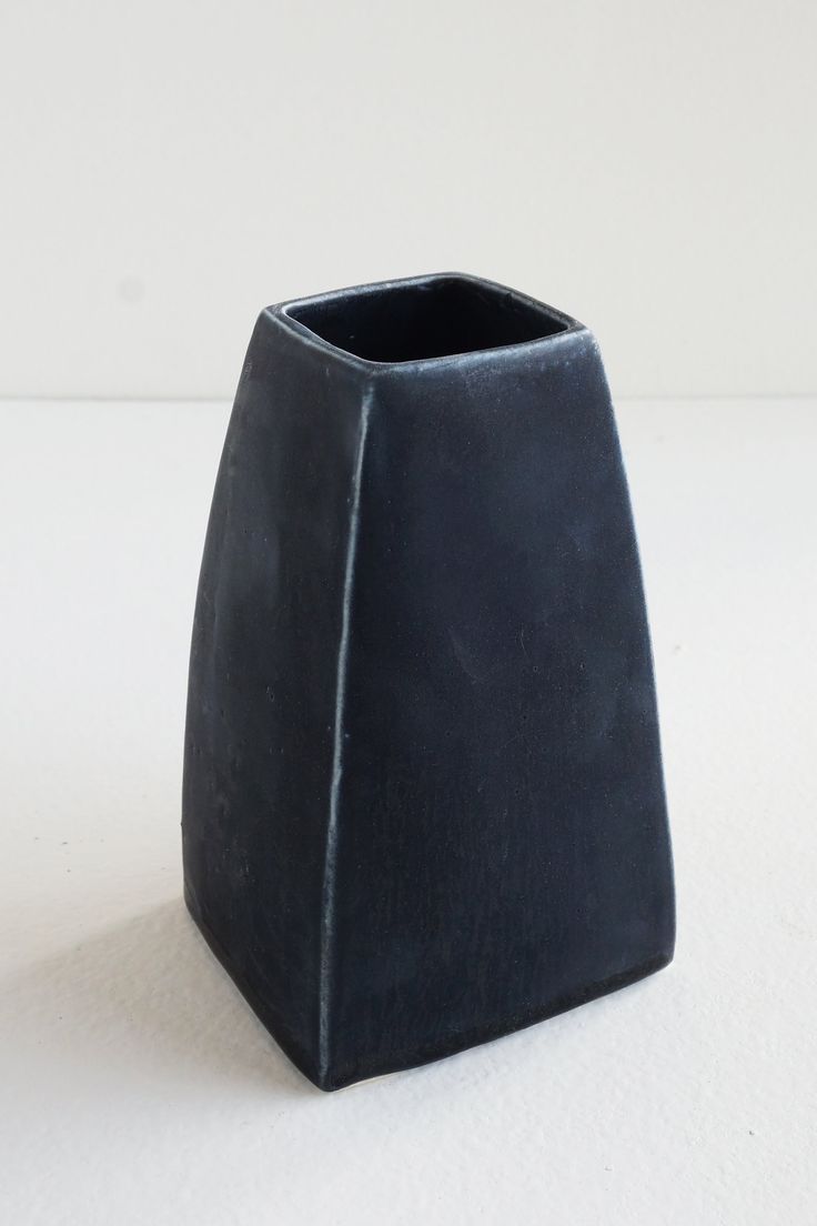 a black vase sitting on top of a white table