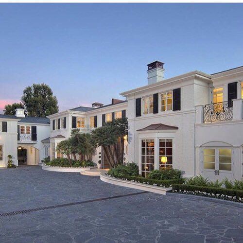 a large white house with lots of windows on the front and side of it at dusk