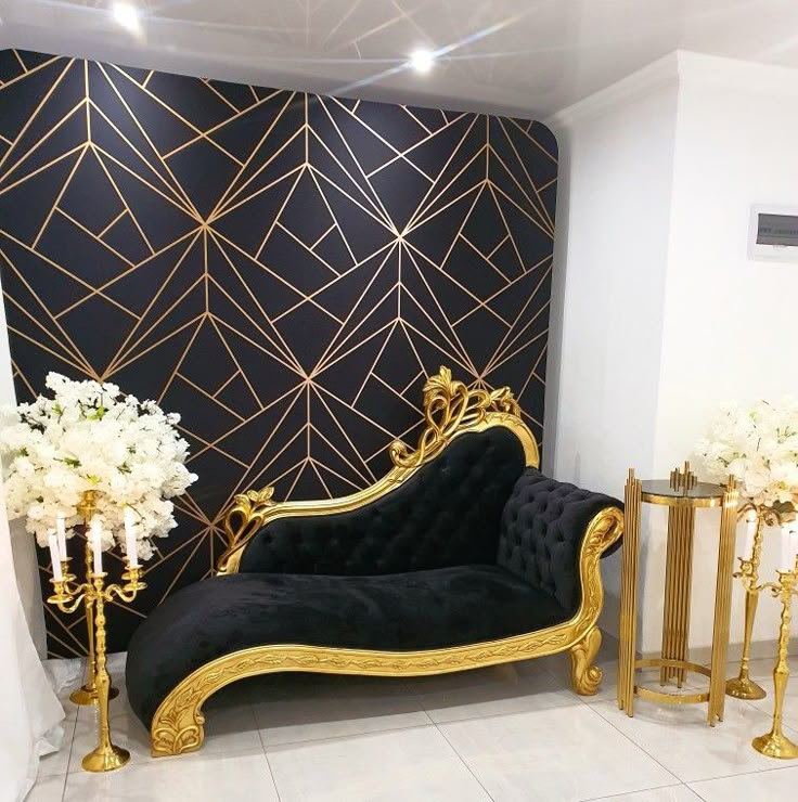 a black and gold couch sitting in front of a wall with white flowers on it