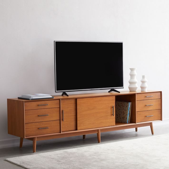 a flat screen tv sitting on top of a wooden entertainment center next to a white rug